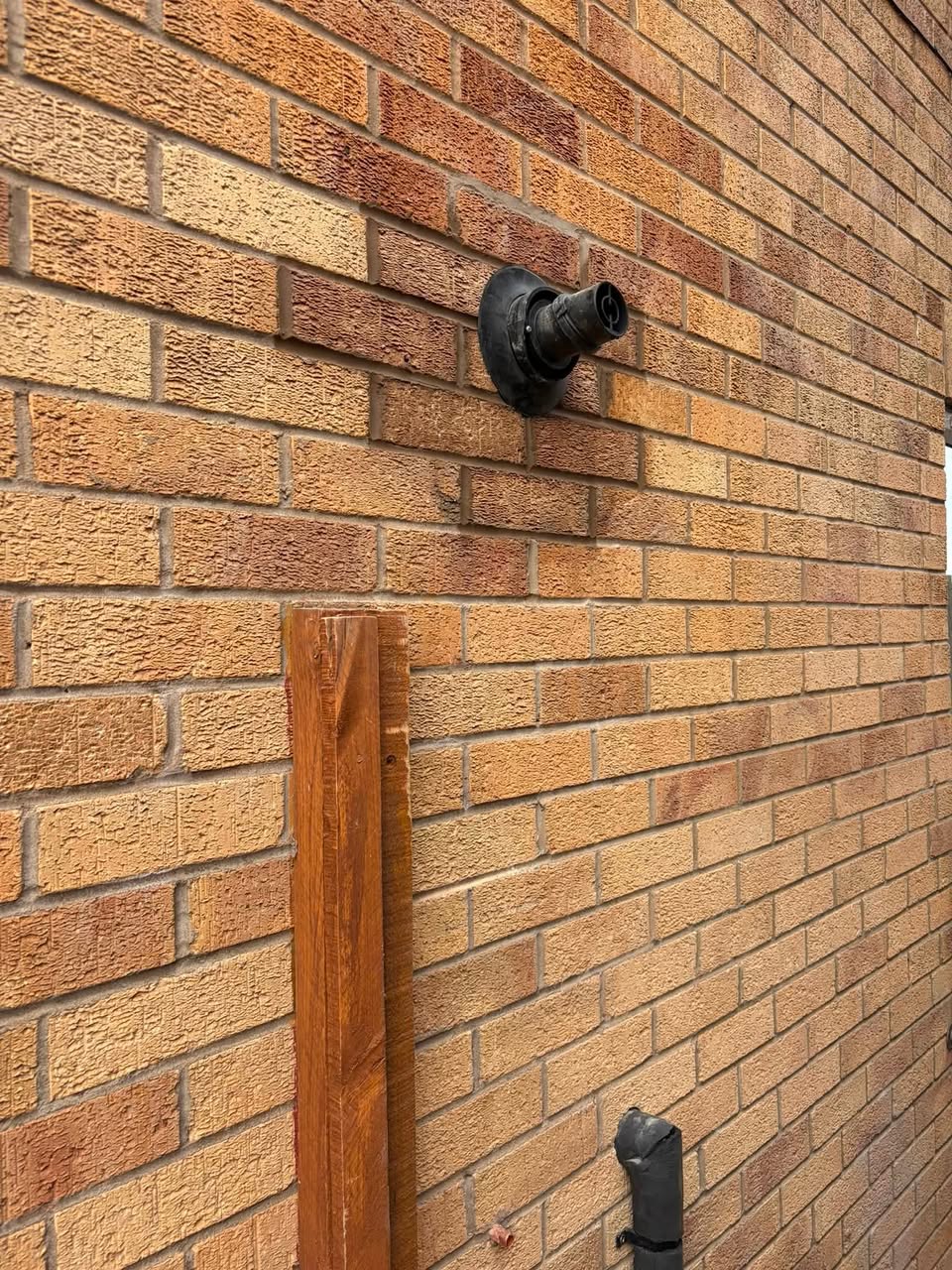 A boiler flue terminal coming through a brick wall, sealed and finished neatly against the brickwork.
