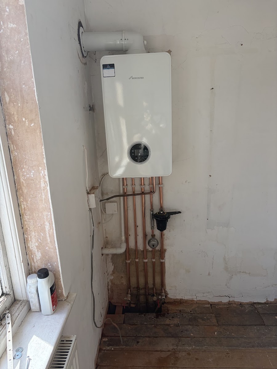 A new white Worcester boiler on a bare wall with five copper pipes dropping neatly beneath it.