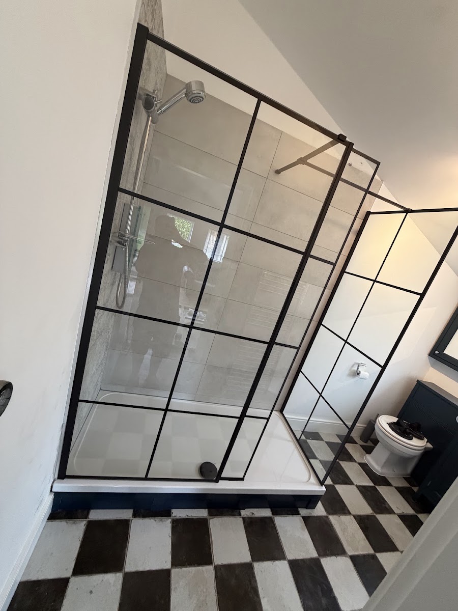 A finished bathroom with a black-framed shower screen and a black and white chequerboard tiled floor.