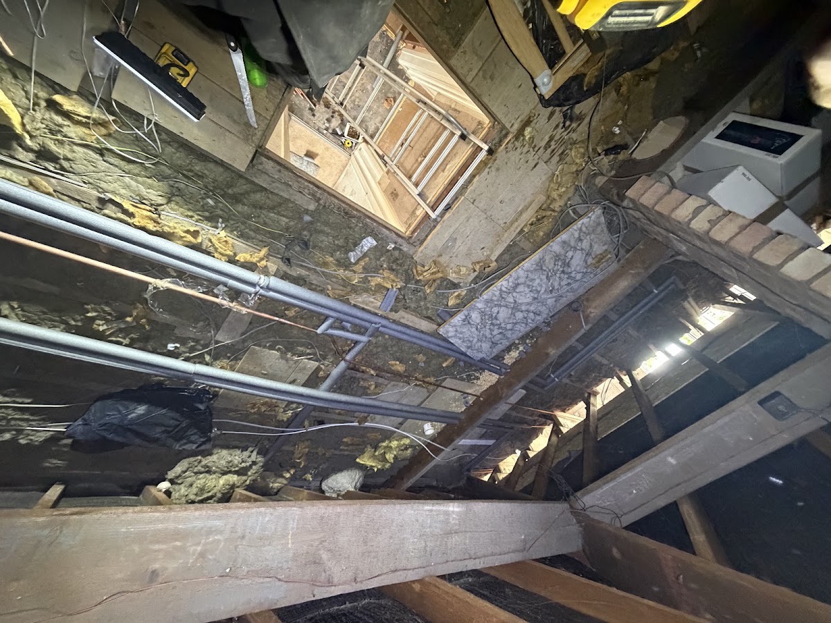 Heating pipework running through a loft between the joists, clipped and supported, with insulation either side.